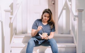 Woman sitting and eating a meal as part of her Ketogenic diet plan to address her autoimmune disease